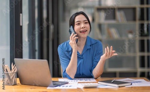 Foto Cheerful business Asian woman freelancer making telephone call share good news about project working in office workplace, business finance concept