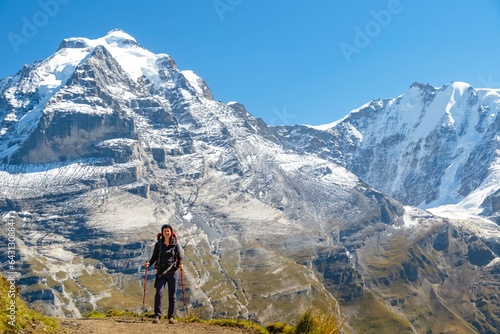 Sporty woman standing in front of snow mountains and enjoying view of Switzerland nature. Wanderlust, sport, beauty in nature. © Kotangens