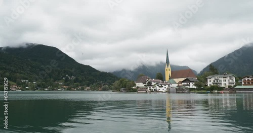 Lake Tegernsee in Bavarian Alps with a view of Rottach-Egern and St. Lawrence Church at the foot of the Alpine peaks under a cloudy sky photo