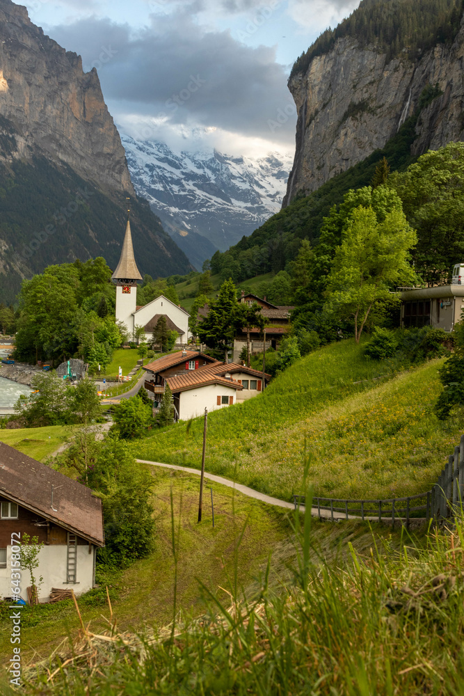 Buildings and a Church Sitting Along the Hills high up in Lauterbrunnen in the Swiss Alps with mountains in the background in Switzerland in Summer