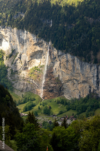 Waterrfall in the Swiss Alps in Switzerland in the Summer With Mountains Peaking Through the Clouds in the Background  photo