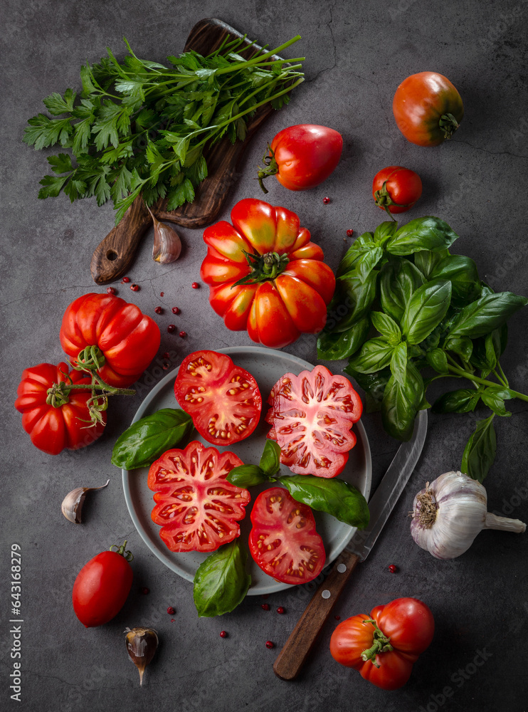 Fresh tomatoes, herbs and garlic on a dark table. View from above Fresh tomatoes, herbs and garlic on a dark table. View from above