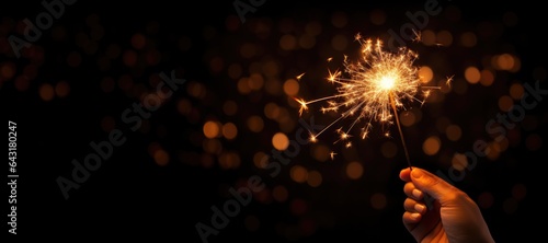 A hand holding a sparkler on a black background photo