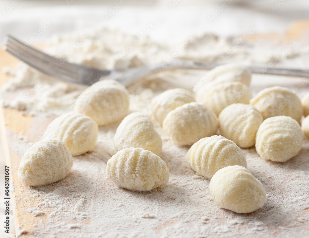 Freshly made flour and potato gnocchi, on a wooden board.