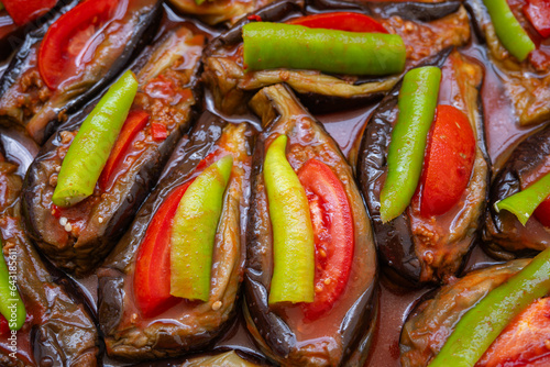 Baked eggplant stuffed with ground beef, tomatoes and green peppers on a tray. Traditional delicious Turkish food. Riven belly - Karniyarik. Turkish cuisine. Aubergine eggplant meal. Close up Top view