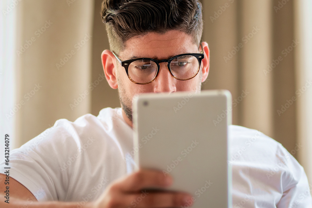 Close-up of a middle-aged man sitting at home on the sofa and holding a digital tablet in his hand