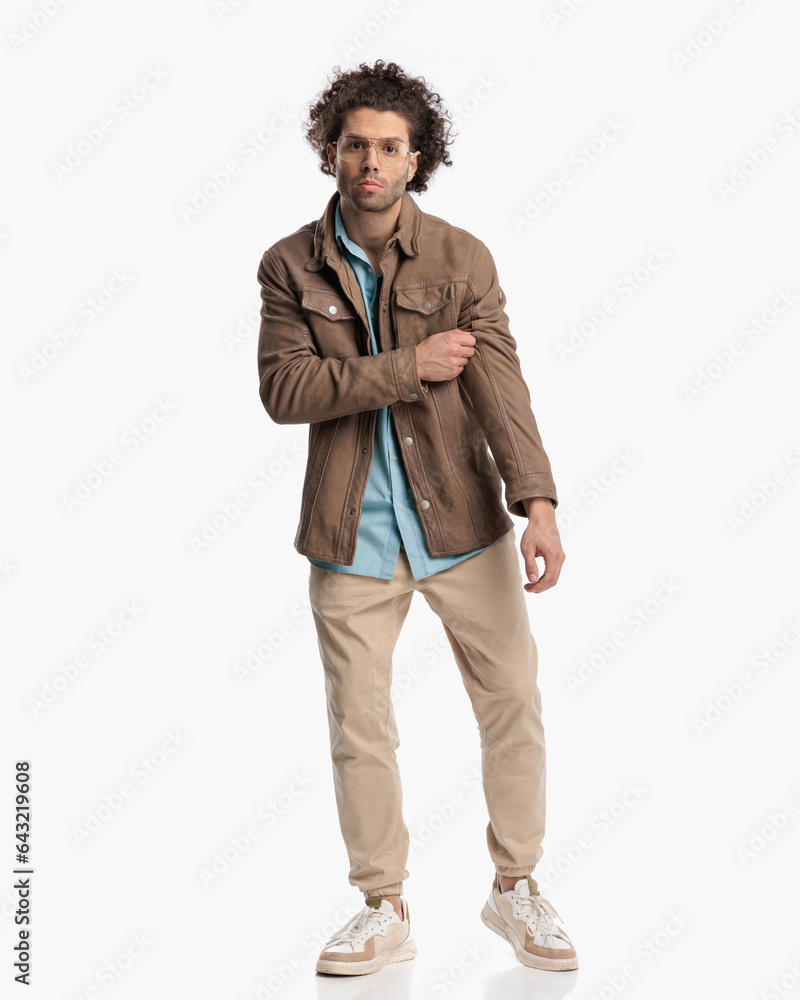 Naklejka premium handsome man with glasses adjusting jacket and walking