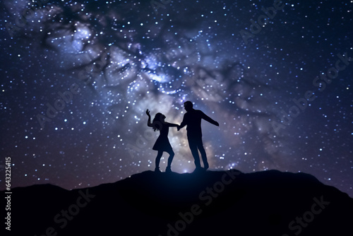 Silhouette of a Romantic couple Dancing on top of mountain and looking at starry sky. © soysuwan123
