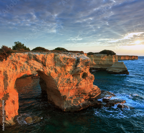 Picturesque seascape with cliffs, rocky arch and stacks (faraglioni), at Torre Sant Andrea in morning sunlight, Salento sea coast, Puglia, Italy.