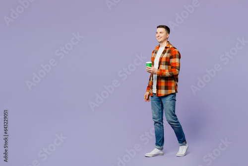 Full body side view young happy man he wearing checkered shirt white t-shirt casual clothes hold takeaway delivery craft paper brown cup coffee to go isolated on plain pastel light purple background.
