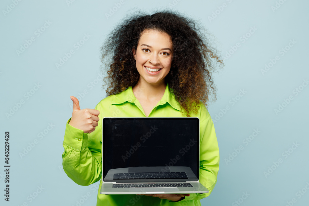 Happy smart young IT latin woman she wear green shirt casual clothes hold use work on blank screen workspace area laptop pc computer show thumb up isolated on plain pastel light blue cyan background Happy smart young IT latin woman she wear green shirt casual clothes hold use work on blank screen workspace area laptop pc computer show thumb up isolated on plain pastel light blue cyan background