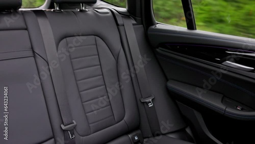 Close-up of rear view interior with leather seats of new black electric car driving on highway. Sweden.