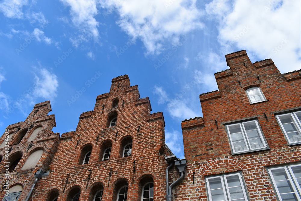 Historic brick facade of antique merchant houses in a town in Germany. Hanseatic merchants build these houses. Blue sky with beautiful white clouds.