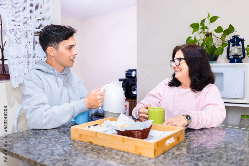 Mature woman and adult son enjoy a traditional Brazilian coffee break at a table, sharing lively conversation in a typical Brazilian home Mature woman and adult son enjoy a traditional Brazilian coffee break at a table, sharing lively conversation in a typical Brazilian home