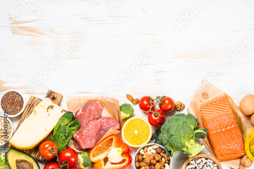 Healthy food products at white. Balanced nutrition. Salmon fish, beef, cheese, beans, nuts and vegetables with olive oil. Top view image with copy space. photo