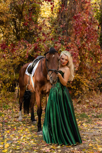 A woman in dress stands next to a horse. Horseback riding in the autumn forest