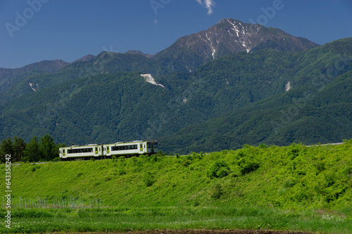 快晴の朝・甲斐駒ヶ岳を背景に大曲りをゆく小海線キハ110系