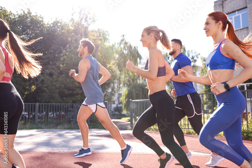 Group of people running at stadium on sunny day