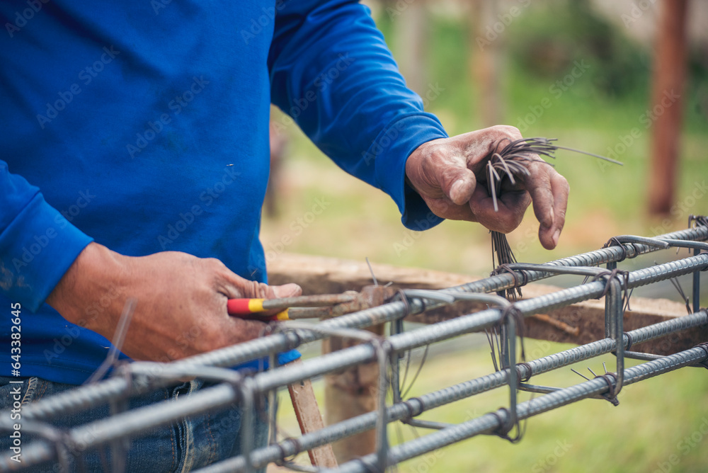 Men hands using pincer pliers iron wire reinforcement of concrete work. Construction Worker hands bending cutting steel wire fences bar. Outdoor Worker using wire bending pliers, construction work. - obrazy, fototapety, plakaty 