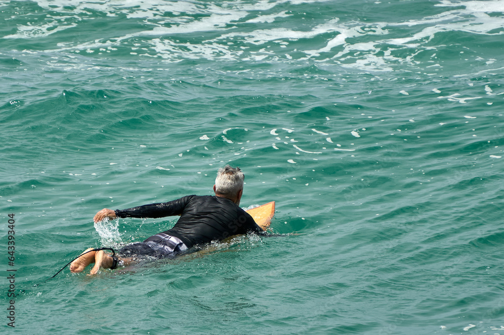 Adventurous Elderly Surfer Riding Waves in Lush Green Sea