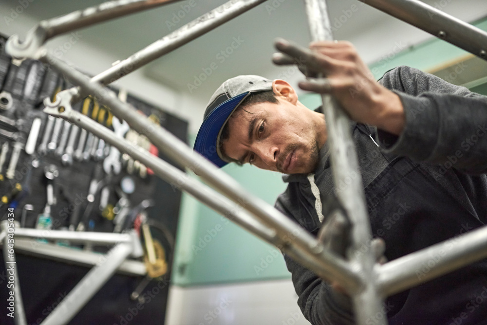 Hispanic man sanding a bicycle frame at his workshop