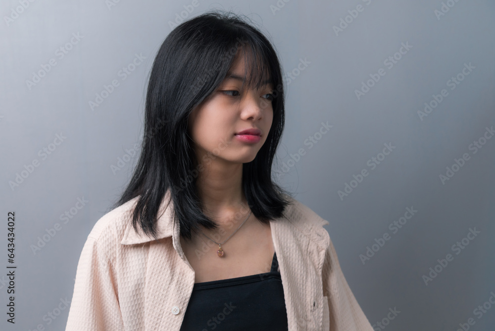 Young beautiful Asian teenage girl showing a sad, disappointed expression on background. Young beautiful Asian teenage girl showing a sad, disappointed expression on background.