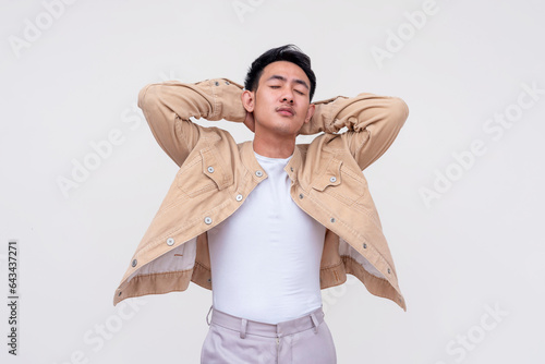 A friendly and handsome FIlipino guy in khaki jacket and white shirt stretching for extra energy after feeling tired. Isolated on a white background.