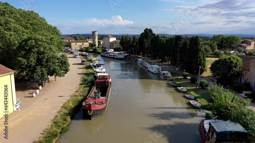 Drone shot, drone video, drone flight, aerial view, flight at low altitude over the Canal du Midi near Le Somail with a wide view over the landscape, camper site, boats and ships on the water photo