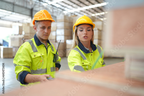 Warehouse worker working at lumber yard in Large Warehouse. Worker are  Inventory check at Storage shelves in lumberyard. © FotoArtist