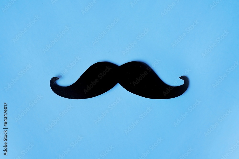 Top view image of fake mustache on blue background with copy space. Masculine, movember and hipster concept Top view image of fake mustache on blue background with copy space. Masculine, movember and hipster concept