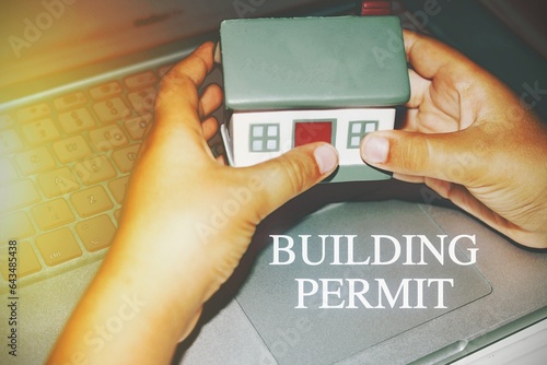 House model hold in two hands with the text “building permit” photo