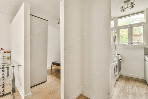a bathroom with white walls and wood flooring the room is well lit by natural light from the large window