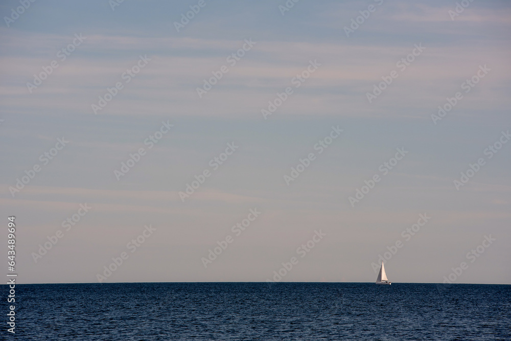 A sailboat heading out to sea on a beautiful summer day