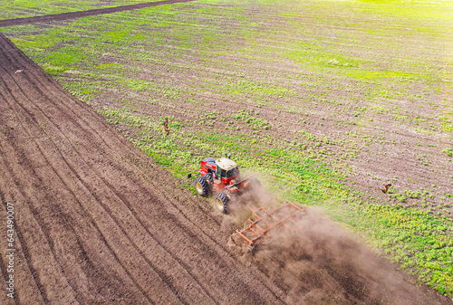 Fototapeta Aerial view of agricultural tractor doing stubble field fall tillage on farmland