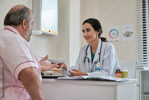 Female doctor and professional nutritionist in uniform advise Caucasian patients about supplementary foods and nutrients for healthy diet at clinic hospital, checkups, and appointments.