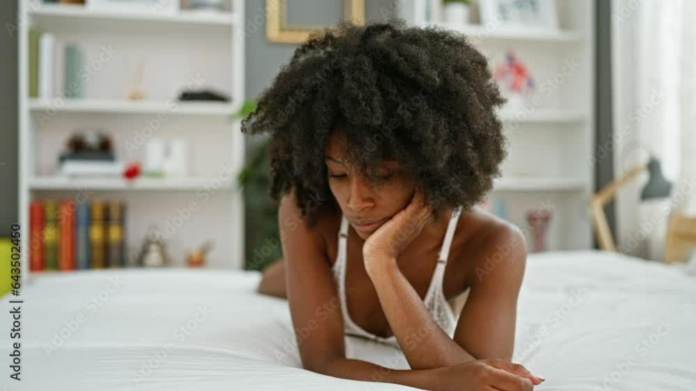 African american woman lying on bed looking sexy thinking at bedroom African american woman lying on bed looking sexy thinking at bedroom
