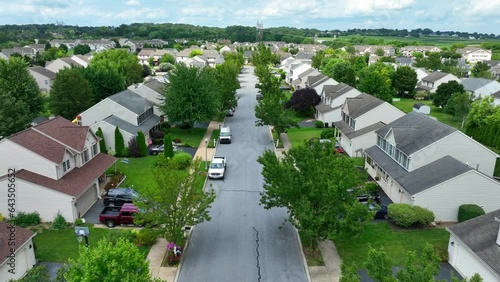 American neighborhood in summer. Aerial dolly forward shot in community of houses and homes. Mature green trees.