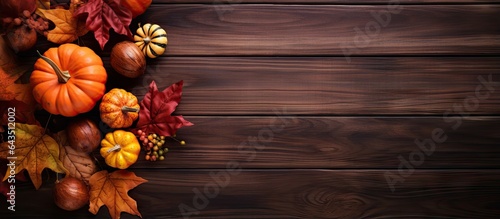 Autumn themed decoration with leaves pumpkins and a wooden background Top view with space for text
