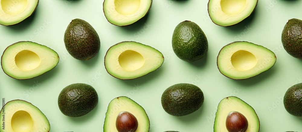 Avocado halves arranged in a pattern on a vibrant mint green background Avocado halves arranged in a pattern on a vibrant mint green background