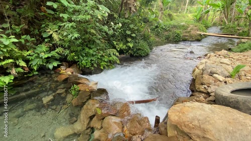 Closeup of the gurgling stream of running water in Kali Umbul Gumuk in Magelang, Indonesia, a river of clear springs showing the riverbed. photo
