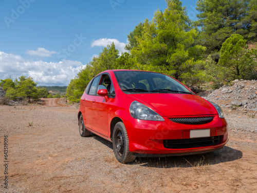 A red subcompact car stands in the mountains in Greece