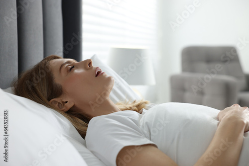 Woman snoring while sleeping in bed at home