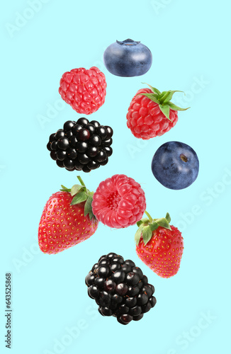 Blackberries, blueberries, strawberries and raspberries falling on light blue background