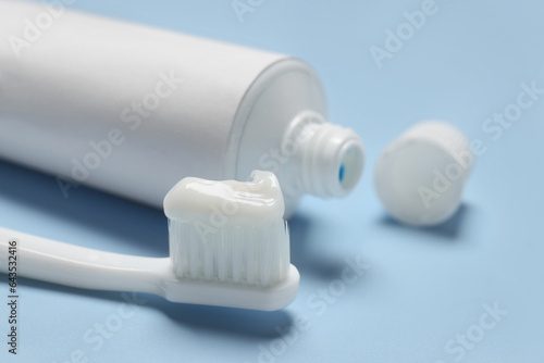 Plastic toothbrush with paste and tube on light background, closeup