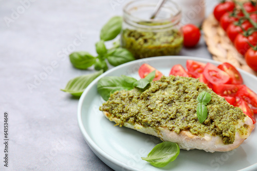 Delicious chicken breast with pesto sauce and basil on light gray table, closeup. Space for text