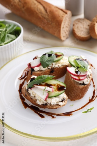 Delicious bruschettas with cream cheese, vegetables and balsamic vinegar on table, closeup