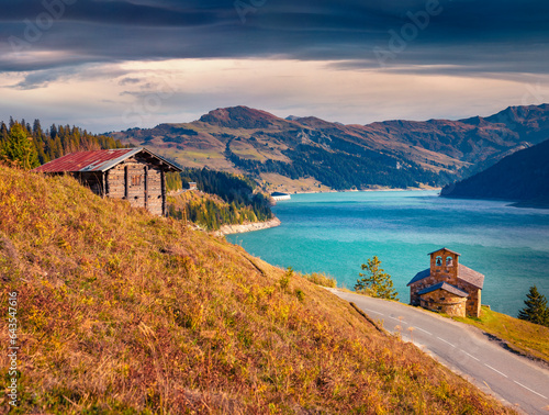 Colorful autumn view of Roselend lake with stone chapel and wooden barn. Stunning morning scene of Auvergne-Rhone-Alpes, France, Europe. Beauty of nature concept background. photo