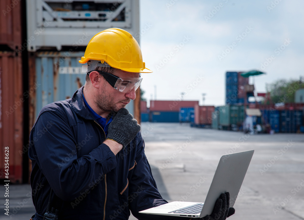 Concepts of Logistic ,import and export . An Engineer dock worker in protective safety jumpsuit uniform use laptop to check and control job at the cargo container shipping warehouse. Concepts of Logistic ,import and export . An Engineer dock worker in protective safety jumpsuit uniform use laptop to check and control job at the cargo container shipping warehouse.