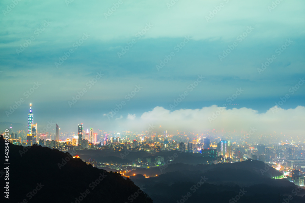 City lights and changing clouds: a spectacle viewed from the top of a mountain. View of the urban landscape from Dajianshan Mountain, New Taipei City, Taiwan.