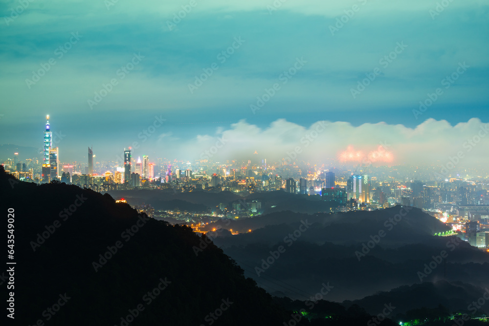 Nocturnal Marvel: City Lights and Shifting Cloudscape from the Summit. View of the urban landscape from Dajianshan Mountain, New Taipei City, Taiwan.